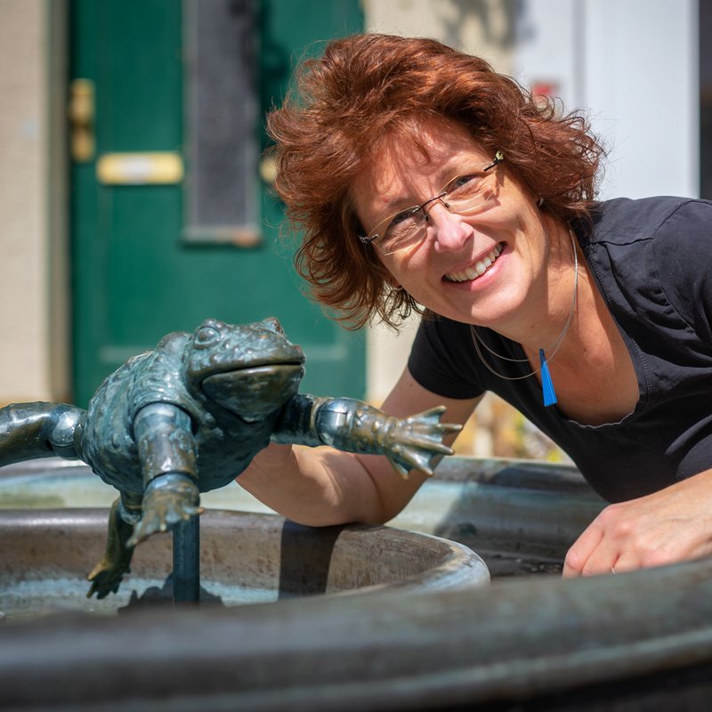 Portrait: Autorin/Illustratorin Anke Faust am Brunnen mit Froschfigur