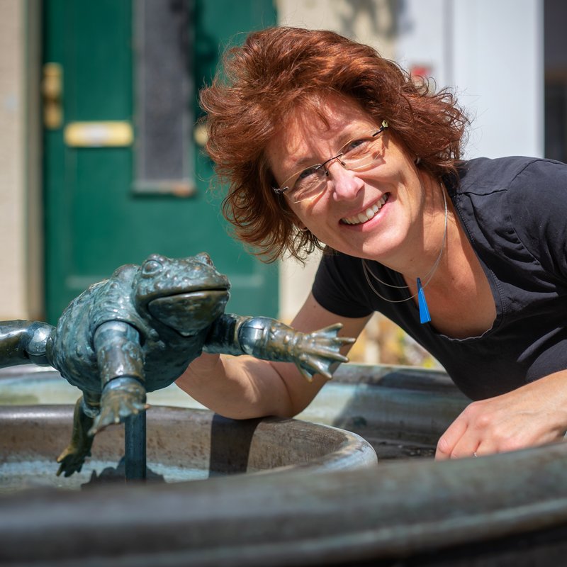 Portrait: Autorin/Illustratorin Anke Faust am Brunnen mit Froschfigur